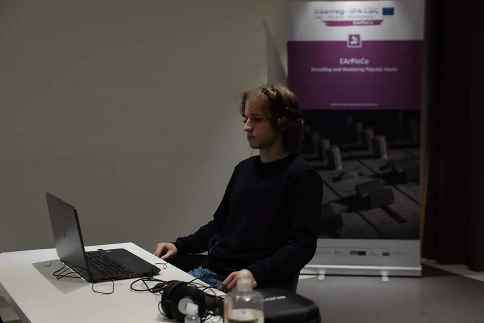 A listener wearing sensors on his head at a computer, an EArPieCe banner behind him
