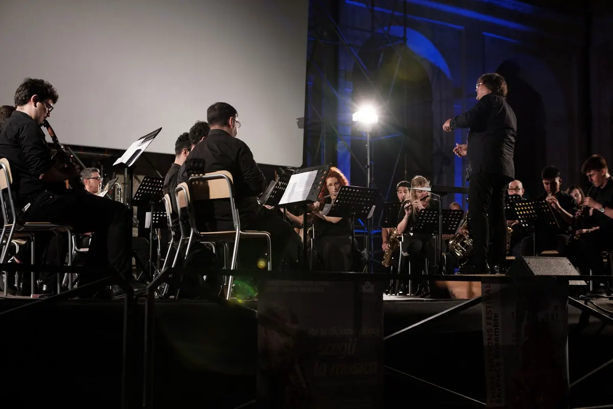 The conductor in front of the orchestra, blue light on the wall behind the stage