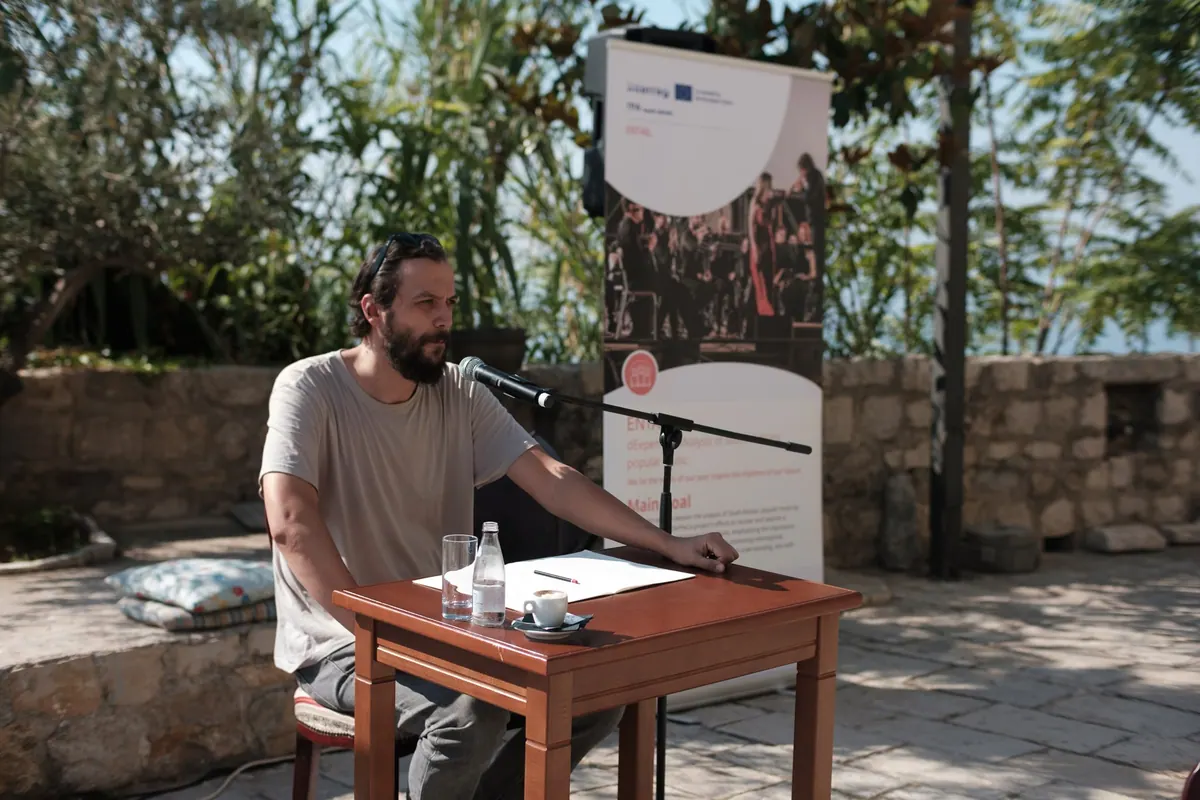 A reading at a table with a microphone, an ENTAIL banner behind