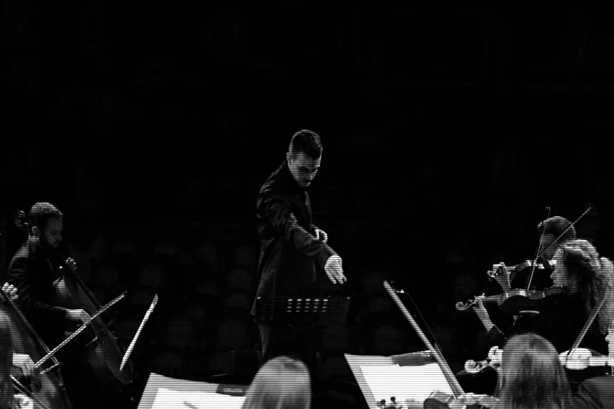 The conductor pointing towards the strings during a concert