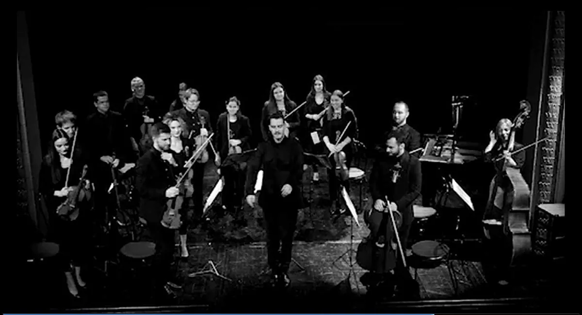 The orchestra standing on stage at the end of a concert
